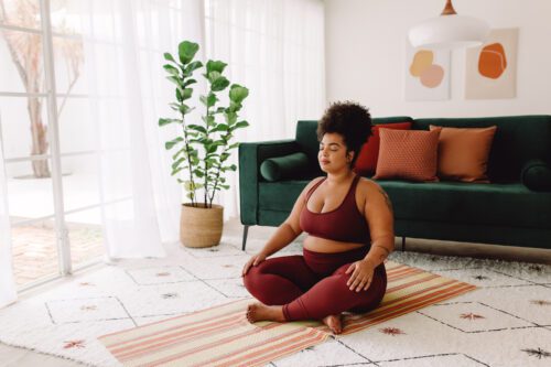 body positive female practicing mindfulness at home and understanding that just because she is on a budget she does not need to compromise on self love